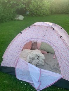 a pink and white tent sitting on top of a lush green field