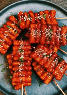 several skewered meats with sesame seeds and seasoning on a blue plate