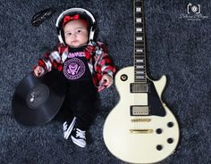 a baby is sitting next to an electric guitar and record player's headphones