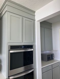 an oven and microwave in a kitchen with gray cabinets on either side of the stove