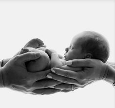 a person holding a baby in their hands while another holds the infant's hand