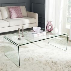 a glass coffee table sitting on top of a rug in front of a white couch