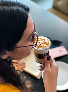 a woman with glasses on her face is drinking from a cup filled with ice cream