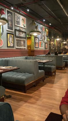 an empty restaurant with blue booths and pictures on the wall above them, along with wood flooring