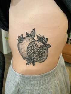 an apple and pomegranate tattoo on the back of a woman's stomach