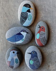 three birds painted on rocks sitting on top of a cement floor next to each other