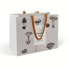 a paper bag with mushrooms on it and an orange ribbon hanging from the front pocket