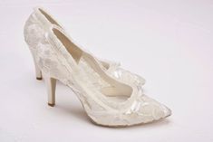 a pair of white high heeled shoes with bows on the toe and lace detailing