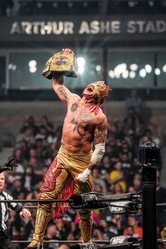 the wrestler is holding up his hat in front of an audience