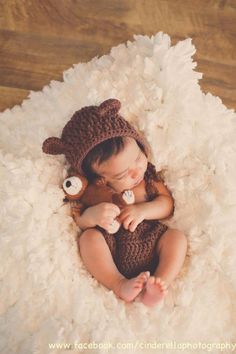 a baby in a bear hat sleeping on a fluffy rug