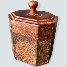 an old wooden box with carvings on the front and sides, sitting against a gray background