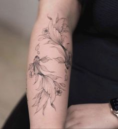 a woman's arm with tattoos on it and flowers in the middle of her arm