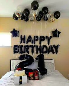 a bed with black balloons and birthday decorations