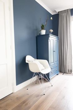 a white chair sitting in front of a blue cabinet