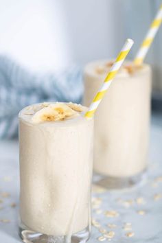 two glasses filled with ice cream and banana slices on top of a blue table cloth