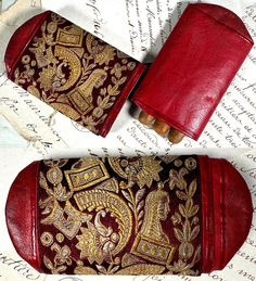 two red and gold purses sitting on top of a piece of paper