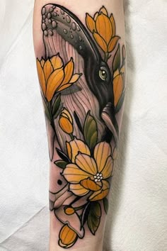 a woman's arm with yellow flowers and a black bird on the left forearm