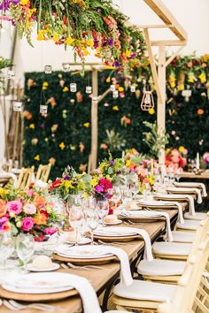 an outdoor dining area with tables and chairs covered in floral arrangements, hanging from the ceiling