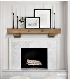 a fireplace with two stools in front of it and some pictures on the mantle