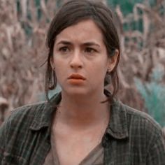 a woman standing in front of a cornfield with her mouth open and looking at the camera