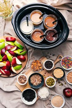 apples, cereals and other ingredients are arranged in bowls on top of a table