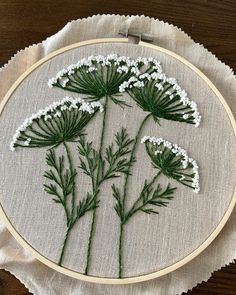 a close up of a embroidery on a piece of cloth with white and green flowers