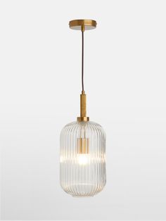 a glass and brass pendant light hanging from a ceiling fixture with an oval, ribbed design