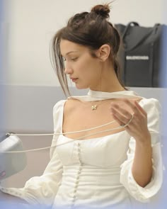 a woman in a white dress looking at her cell phone