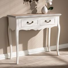 a white table with two drawers and a clock on the wall behind it in a room