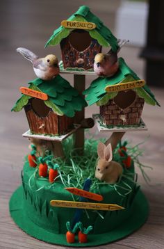 a group of birds sitting on top of a green birdhouse with two rabbits in it