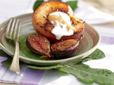 a plate with grilled peaches and whipped cream on top, next to a fork