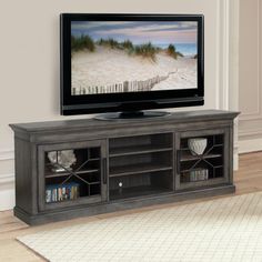 a flat screen tv sitting on top of a wooden entertainment center next to a white rug