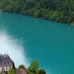 an aerial view of a large house next to a lake in the middle of a forest