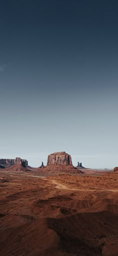 the desert is full of red rocks and brown dirt, under a dark blue sky