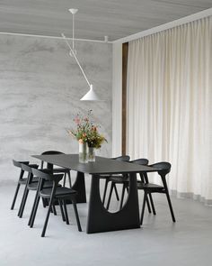 a dining table with four chairs and a vase filled with flowers on top of it