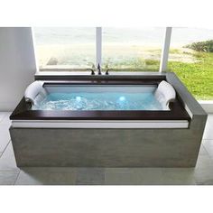 a large bath tub sitting inside of a bathroom next to a window with an ocean view