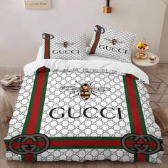 a bed with gucci bee on the cover and pillow cases in red, green and white