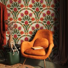 an orange chair sitting in front of a wallpapered room with a book on it