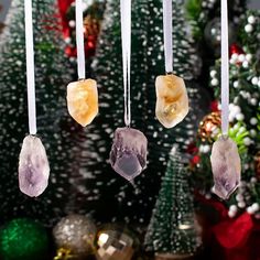 three crystals hanging from strings in front of a christmas tree with other ornaments around it