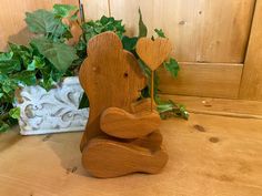 a wooden bear statue sitting next to a potted plant