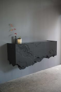 a black shelf with a potted plant on top of it next to a wall