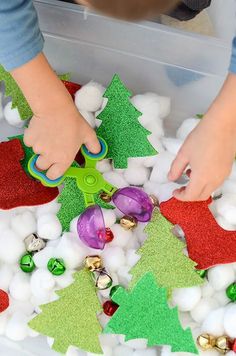 a child is making christmas decorations with cotton balls and plastic spoons in a box