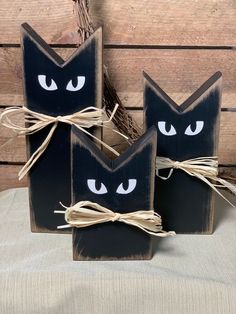 three black wooden blocks with white eyes and twine tied to each other on top of a table