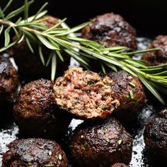 cooked meatballs with rosemary garnish in a skillet, ready to be eaten