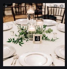 the table is set with candles, plates and silverware for an elegant wedding reception