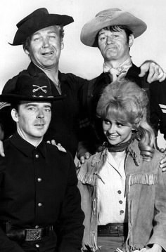 three men and two women in cowboy hats posing for a photo together, one man is holding his arm around the woman's shoulder