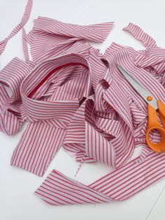 red and white striped fabric being cut by scissors on top of the table next to it