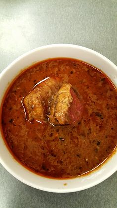 a white bowl filled with soup and meat