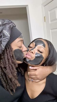 two women with their faces painted black and one is kissing the other's face