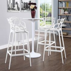 three white bar stools and a table in a room